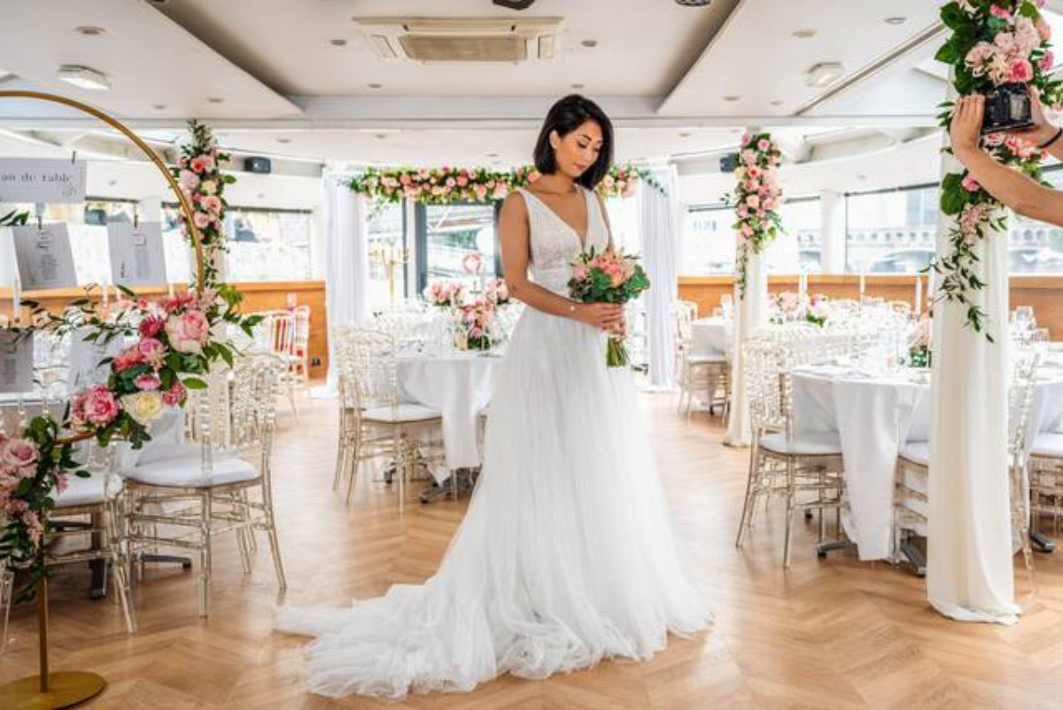 Mariée avançant dans un lieu de mariage original décoré de fleurs, illustrant une cérémonie de mariage en extérieur intime et raffinée